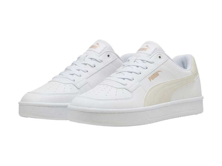Tenis PUMA blancos con detalles en dorado, diseño clásico de corte bajo y suela blanca.