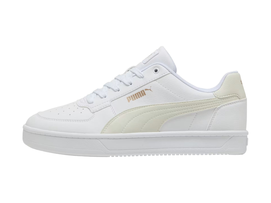 Tenis PUMA blancos con detalles en dorado, diseño clásico de corte bajo y suela blanca.