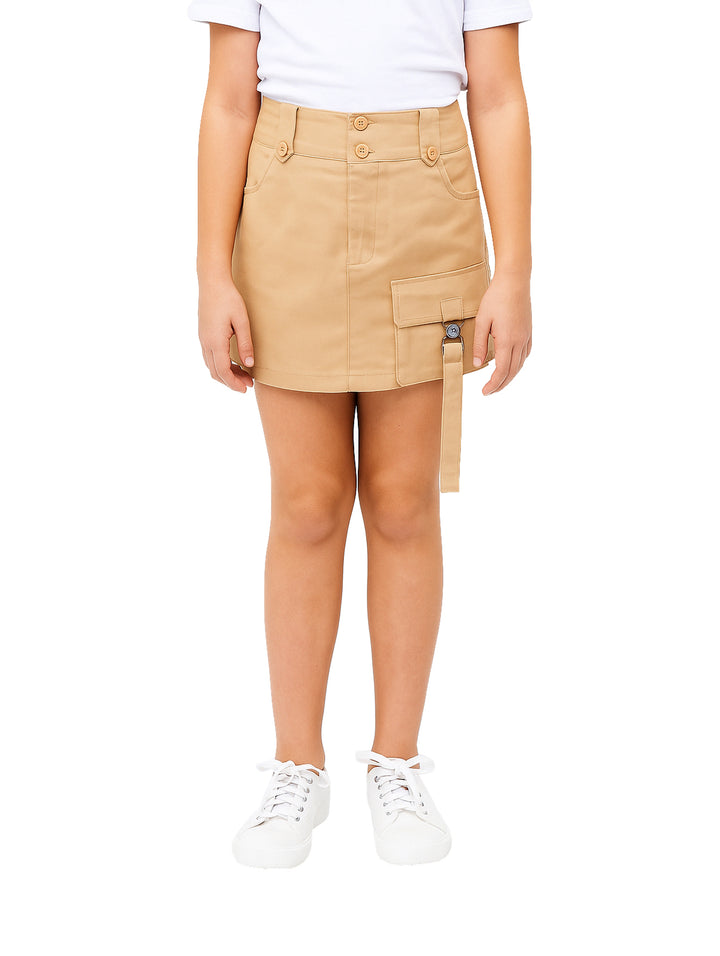 Niña vistiendo una falda corta color khaki con un bolsillo lateral tipo cargo y botones en la cintura.