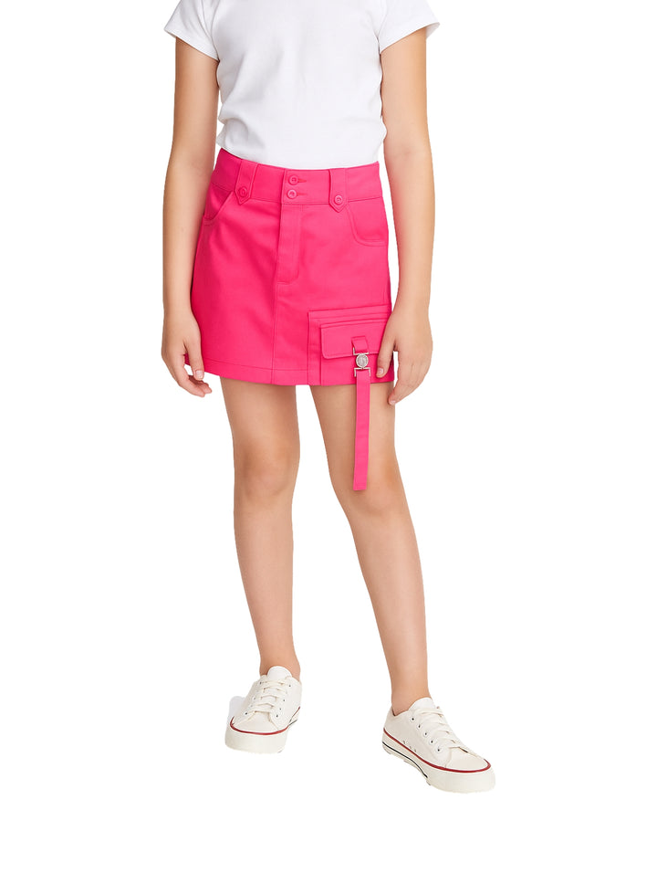 Niña vistiendo una falda corta de color fucsia con un bolsillo lateral y correa colgante.