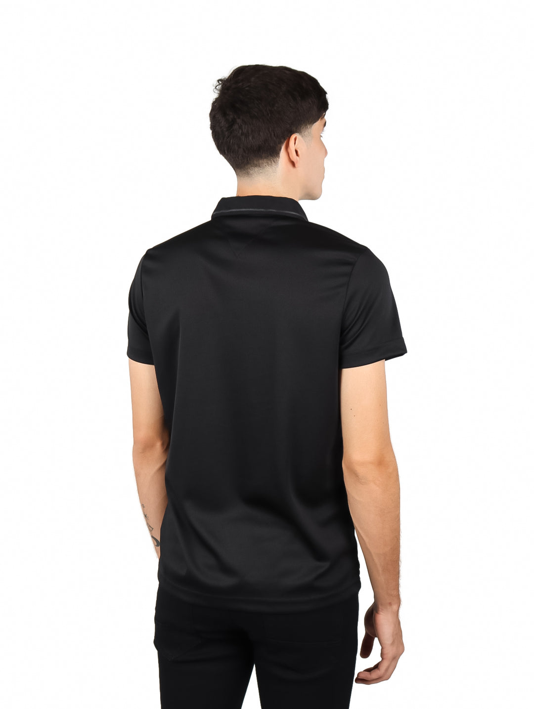 Hombre vistiendo una playera polo de color negro y pantalones negros sobre fondo blanco.