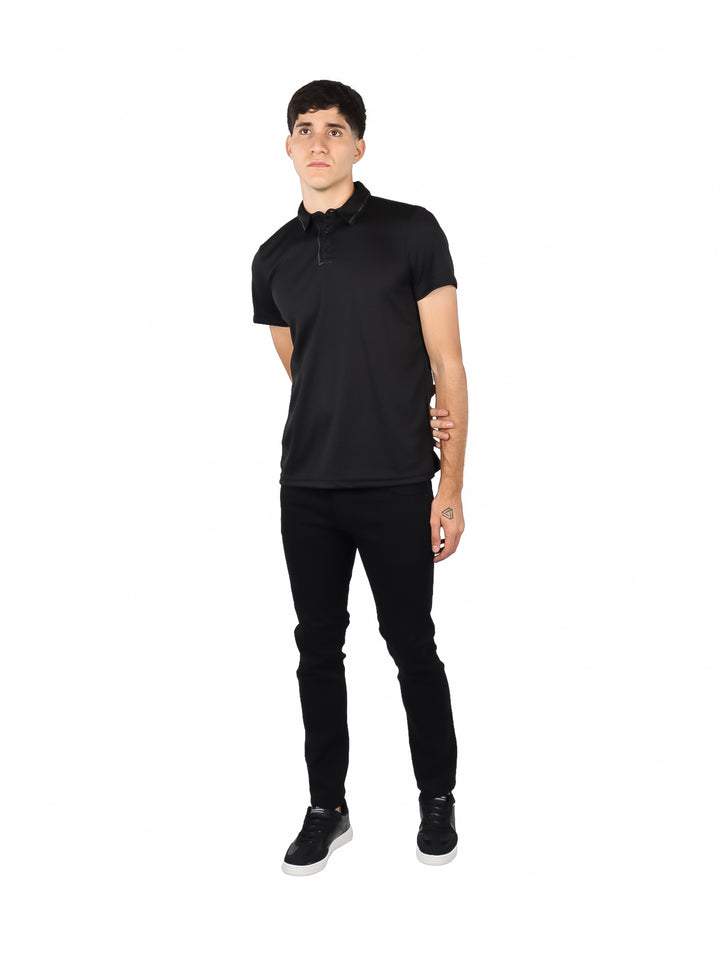 Hombre vistiendo una playera polo de color negro y pantalones negros sobre fondo blanco.