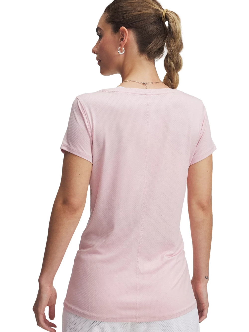 Mujer vistiendo playera deportiva Under Armour de color rosa claro y manga corta.