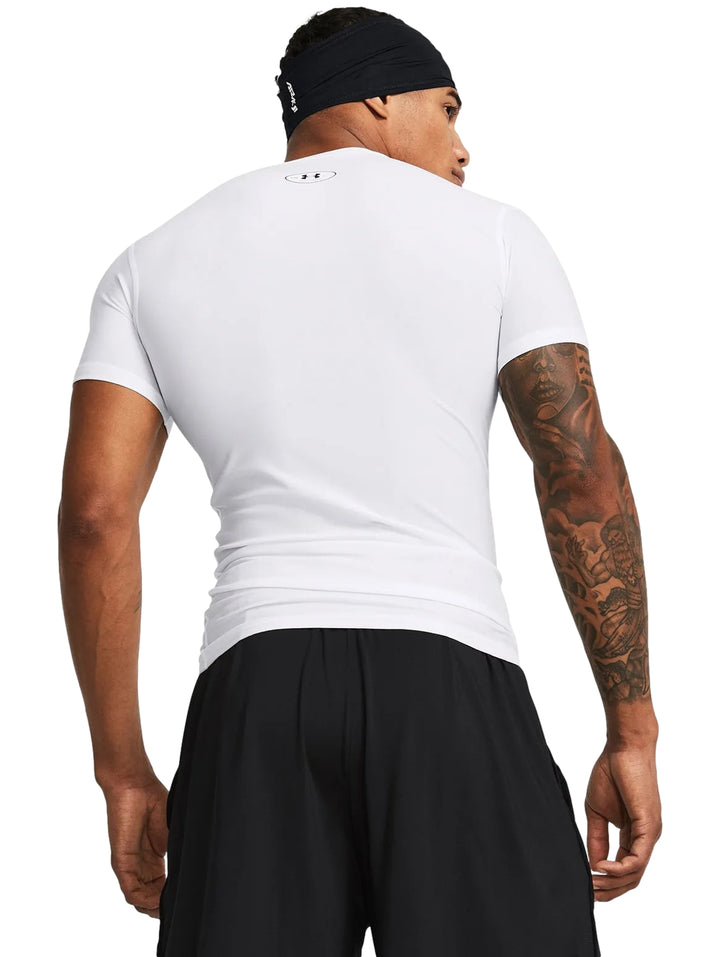 Hombre vistiendo camiseta de compresión blanca de manga corta marca Under Armour.
