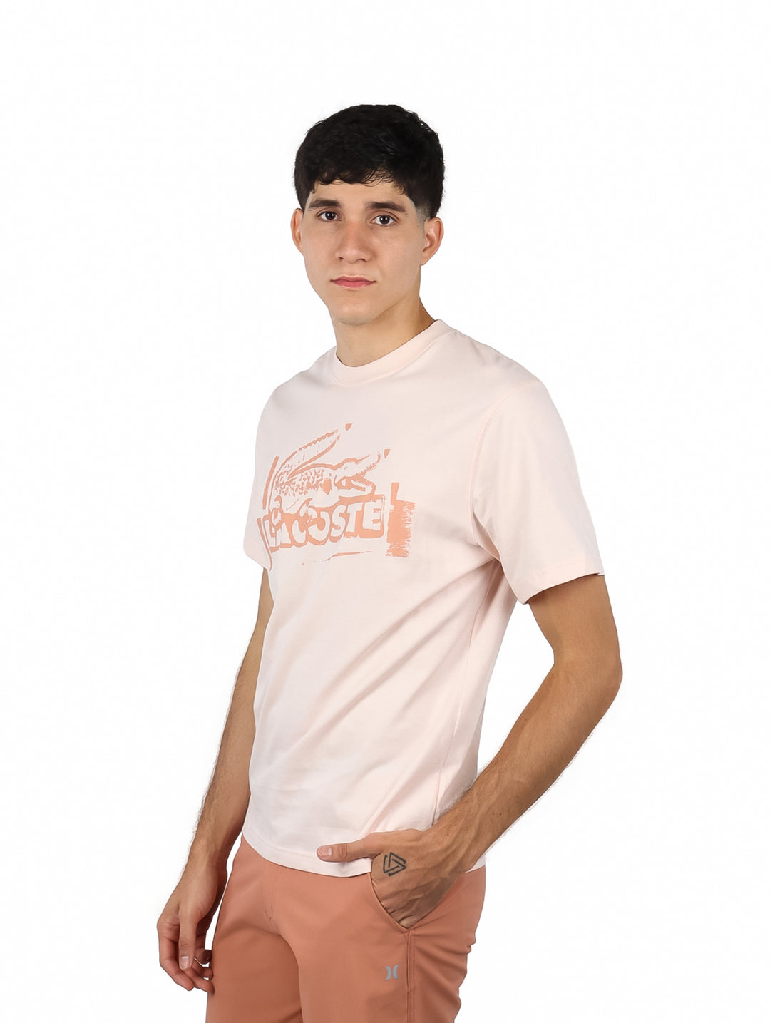 Hombre vistiendo camiseta de manga corta color rosa pálido con gráfico estampado en el frente.