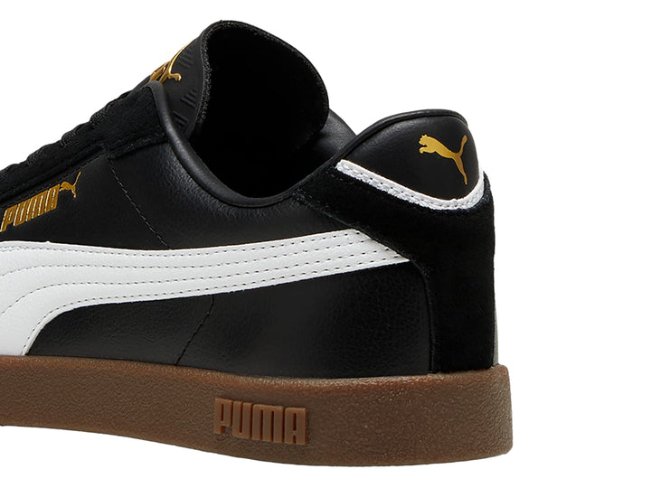 Tenis PUMA color negro con franja blanca lateral y suela de goma color café.