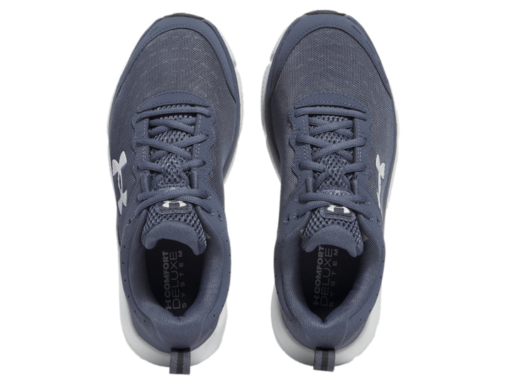 Tenis deportivos Under Armour color gris con suela blanca y logotipo blanco en el costado.