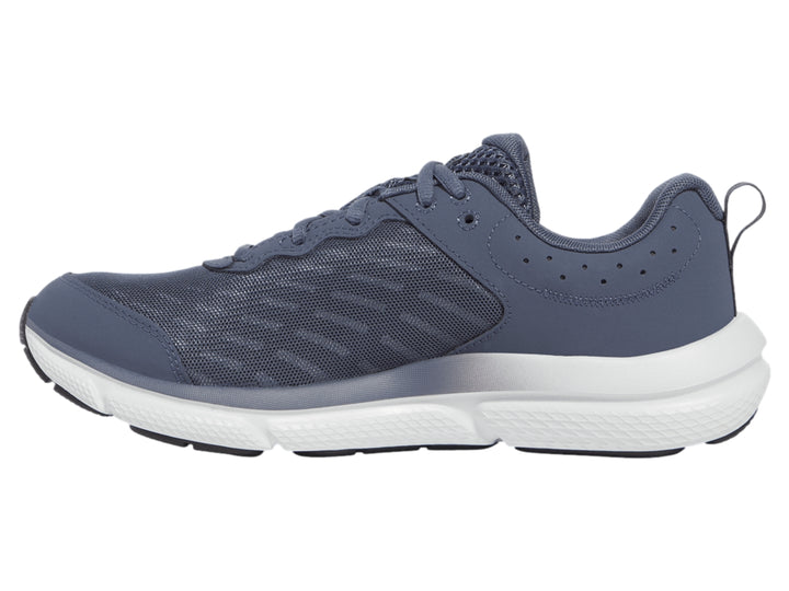 Tenis deportivos Under Armour color gris con suela blanca y logotipo blanco en el costado.
