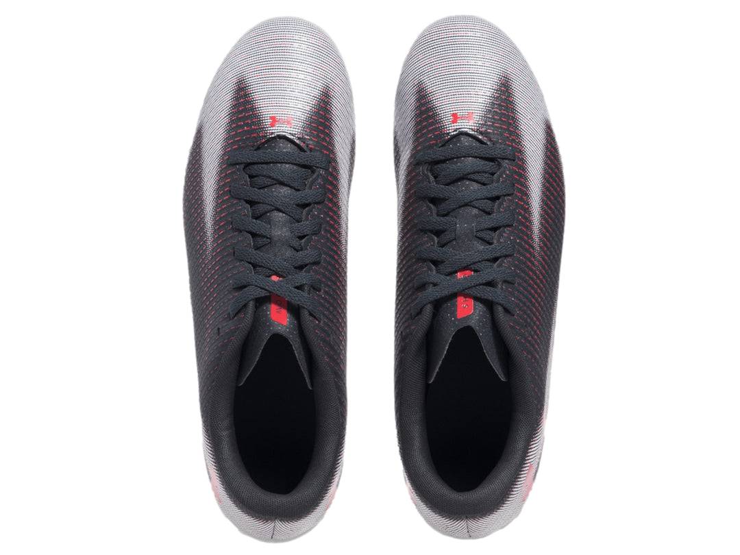 Zapato de fútbol Under Armour color gris con patrón de rayas rojas y suela blanca.