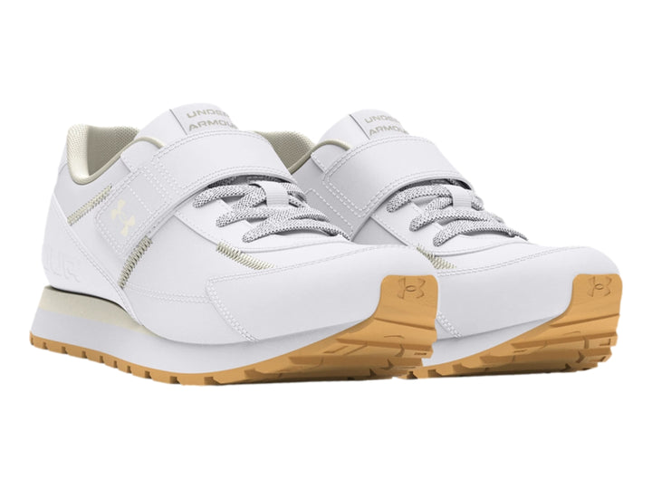 Tenis deportivos Under Armour blancos para niño con cierre de velcro y suela color beige.