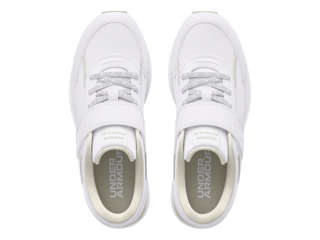 Tenis deportivos Under Armour blancos para niño con cierre de velcro y suela color beige.
