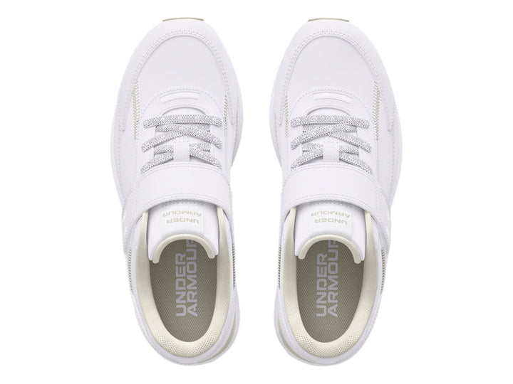 Tenis deportivos Under Armour blancos para niño con cierre de velcro y suela color beige.