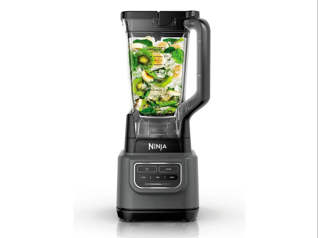 Licuadora Ninja Professional en color negro y gris con vaso de plástico transparente lleno de frutas verdes.