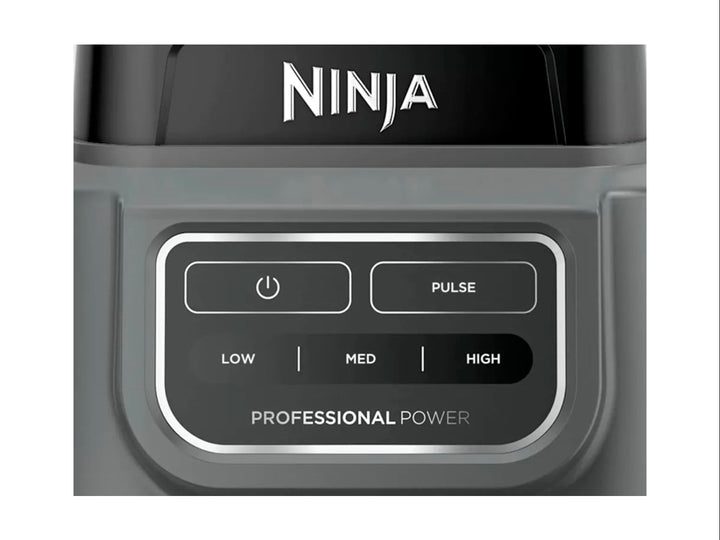 Licuadora Ninja Professional en color negro y gris con vaso de plástico transparente lleno de frutas verdes.
