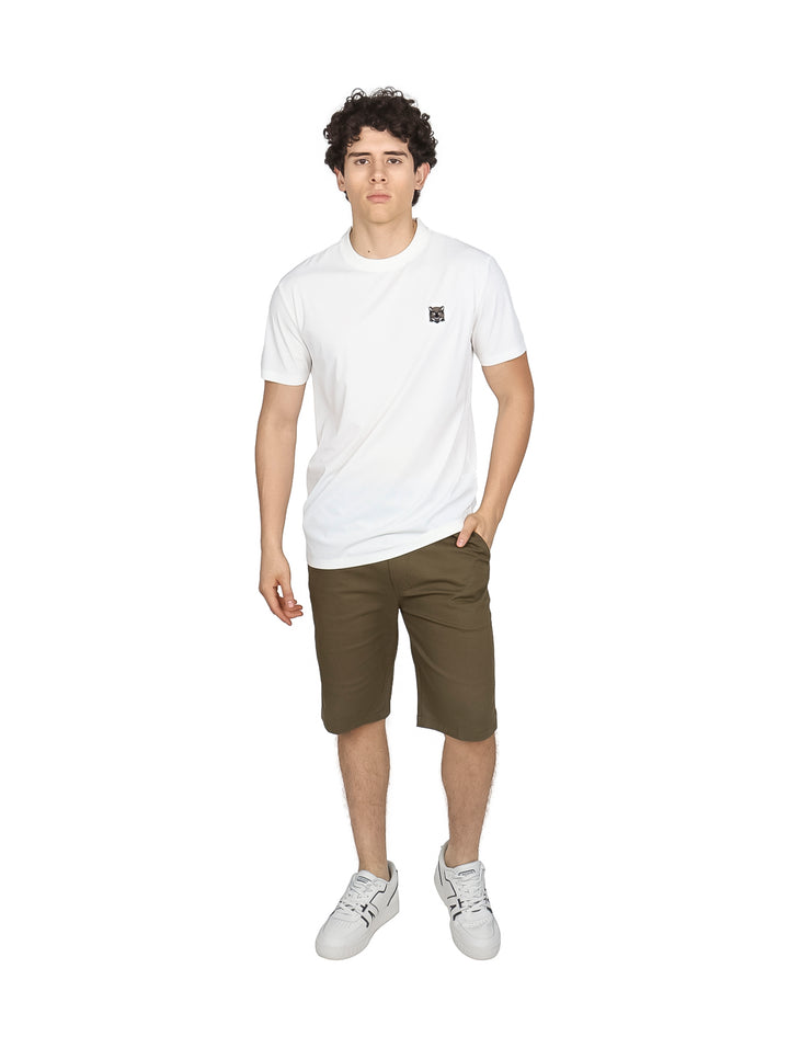 Hombre vistiendo una playera blanca de manga corta con un pequeño logo negro en el pecho.