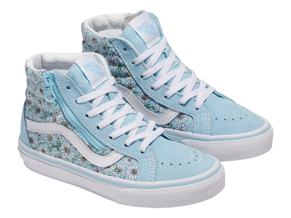 Tenis Vans azul con estampado de margaritas blancas, cierre lateral y suela blanca.