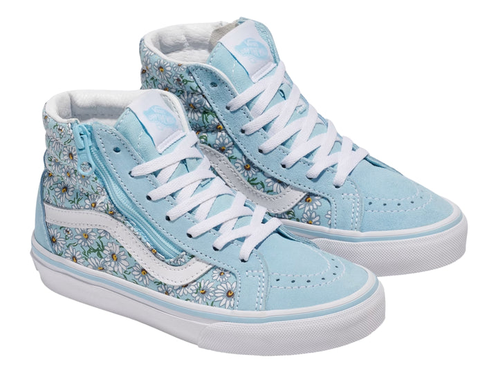 Tenis Vans azul con estampado de margaritas blancas, cierre lateral y suela blanca.
