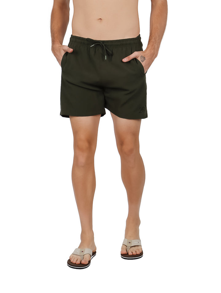 Hombre vistiendo un traje de baño corto color verde militar con cintura elástica y cordón.