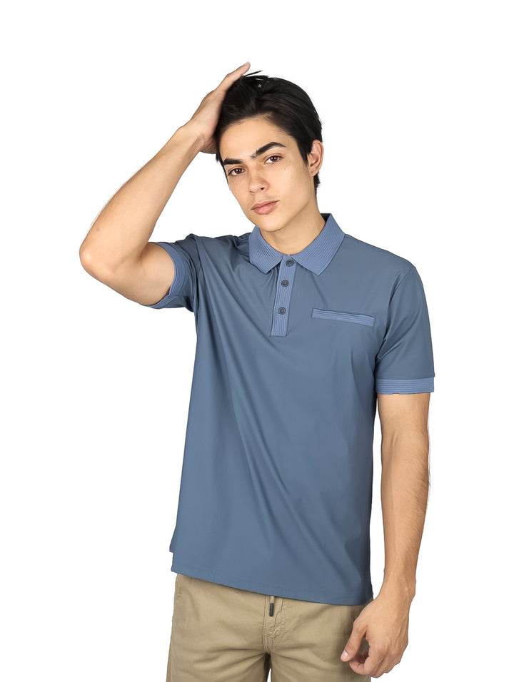 Hombre vistiendo una playera polo de color gris con cuello y detalles en el bolsillo.