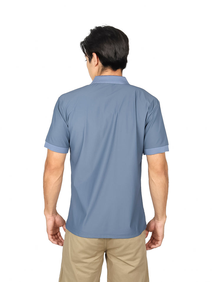Hombre vistiendo una playera polo de color gris con cuello y detalles en el bolsillo.