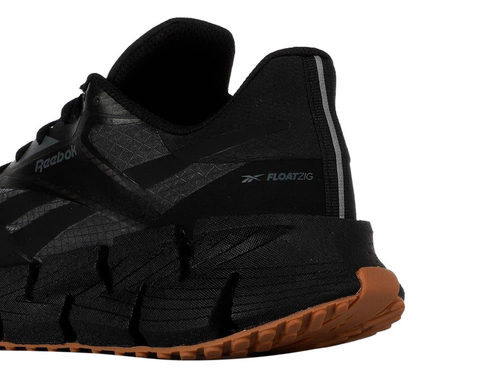 Tenis deportivos Reebok color negro con suela segmentada y base de goma marrón.