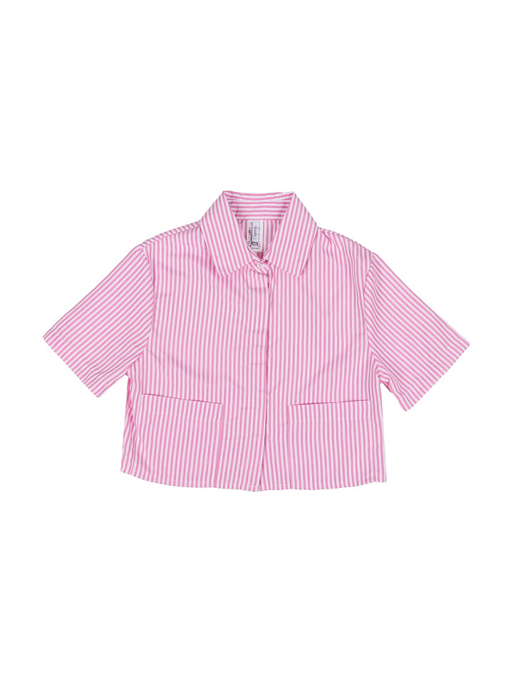 Niña vistiendo una camisa rosa con rayas blancas verticales, manga corta y cuello, combinada con pantalones azules.