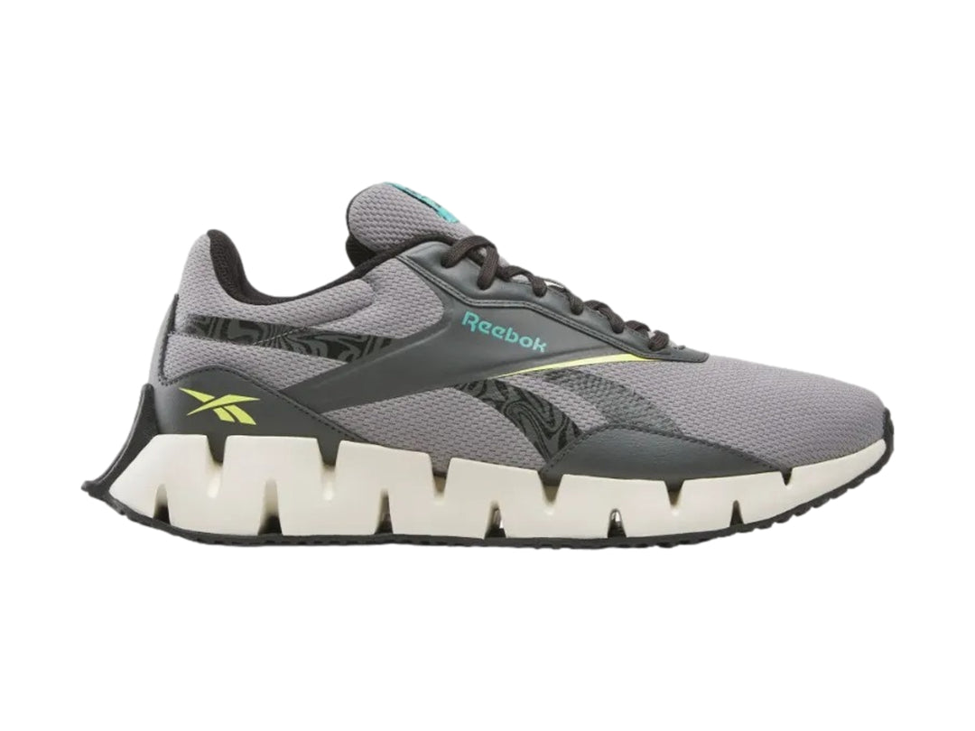Tenis deportivos Reebok en color gris con suela blanca en forma de zig-zag.