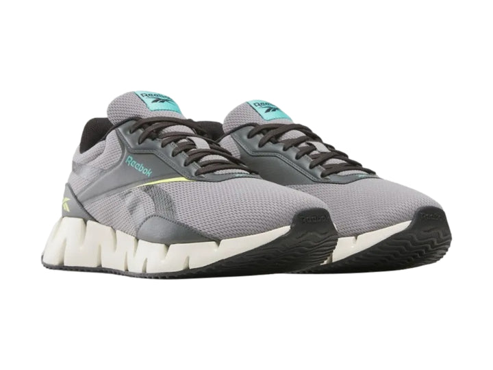 Tenis deportivos Reebok en color gris con suela blanca en forma de zig-zag.