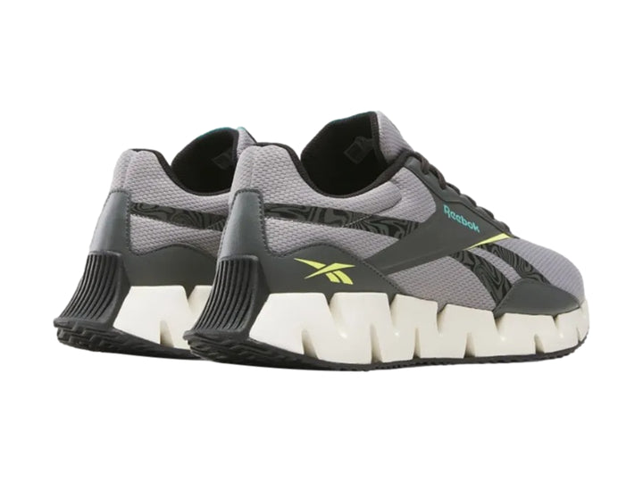 Tenis deportivos Reebok en color gris con suela blanca en forma de zig-zag.