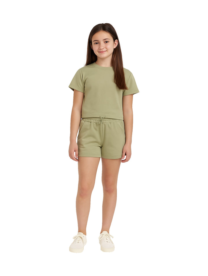 Niña vistiendo un conjunto de camiseta y shorts en color verde oliva.