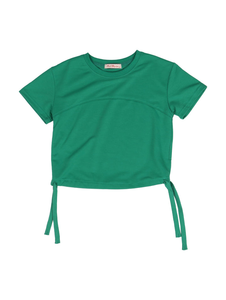 Niña vistiendo un conjunto de camiseta y short color verde con tenis blancos.