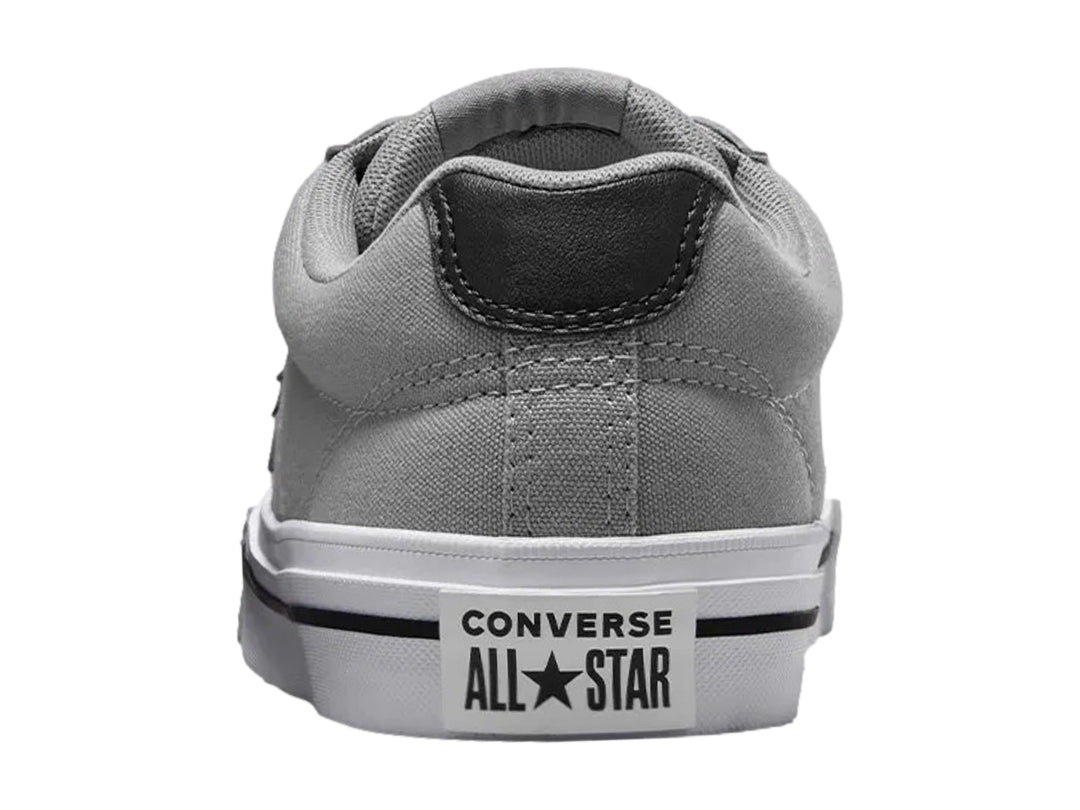 Tenis Converse color gris con suela blanca y detalles en negro, vista lateral.