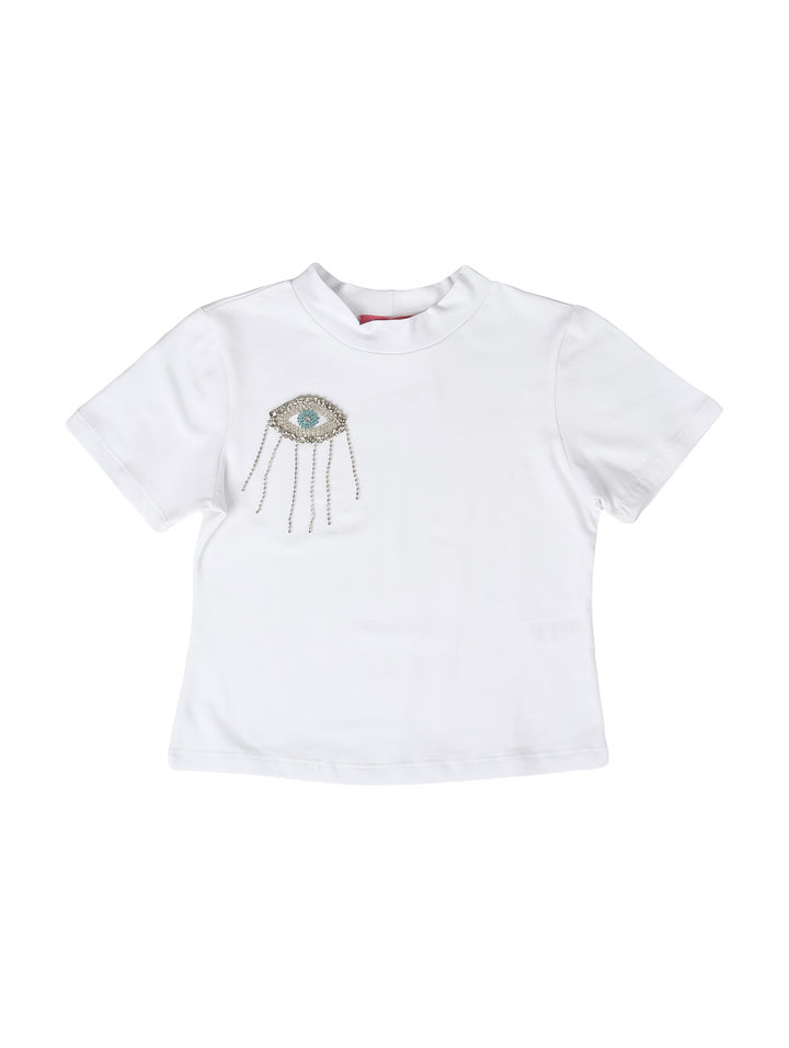 Blusa blanca para niña de manga corta con adorno brillante en forma de ojo y flecos en el pecho.