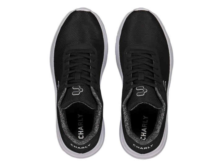 Tenis deportivos Charly color negro con suela blanca y logotipo blanco en el costado.