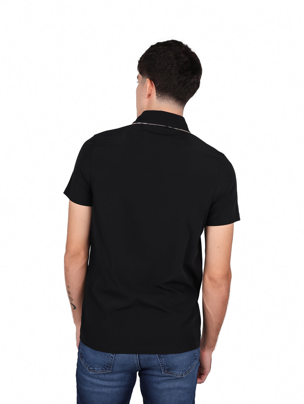 Hombre vistiendo una playera tipo polo de color negro con un pequeño detalle marrón en el pecho.