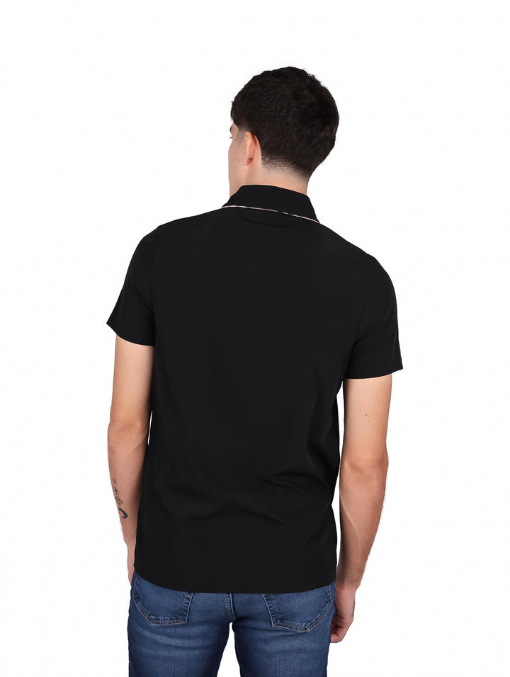 Hombre vistiendo una playera tipo polo de color negro con un pequeño detalle marrón en el pecho.