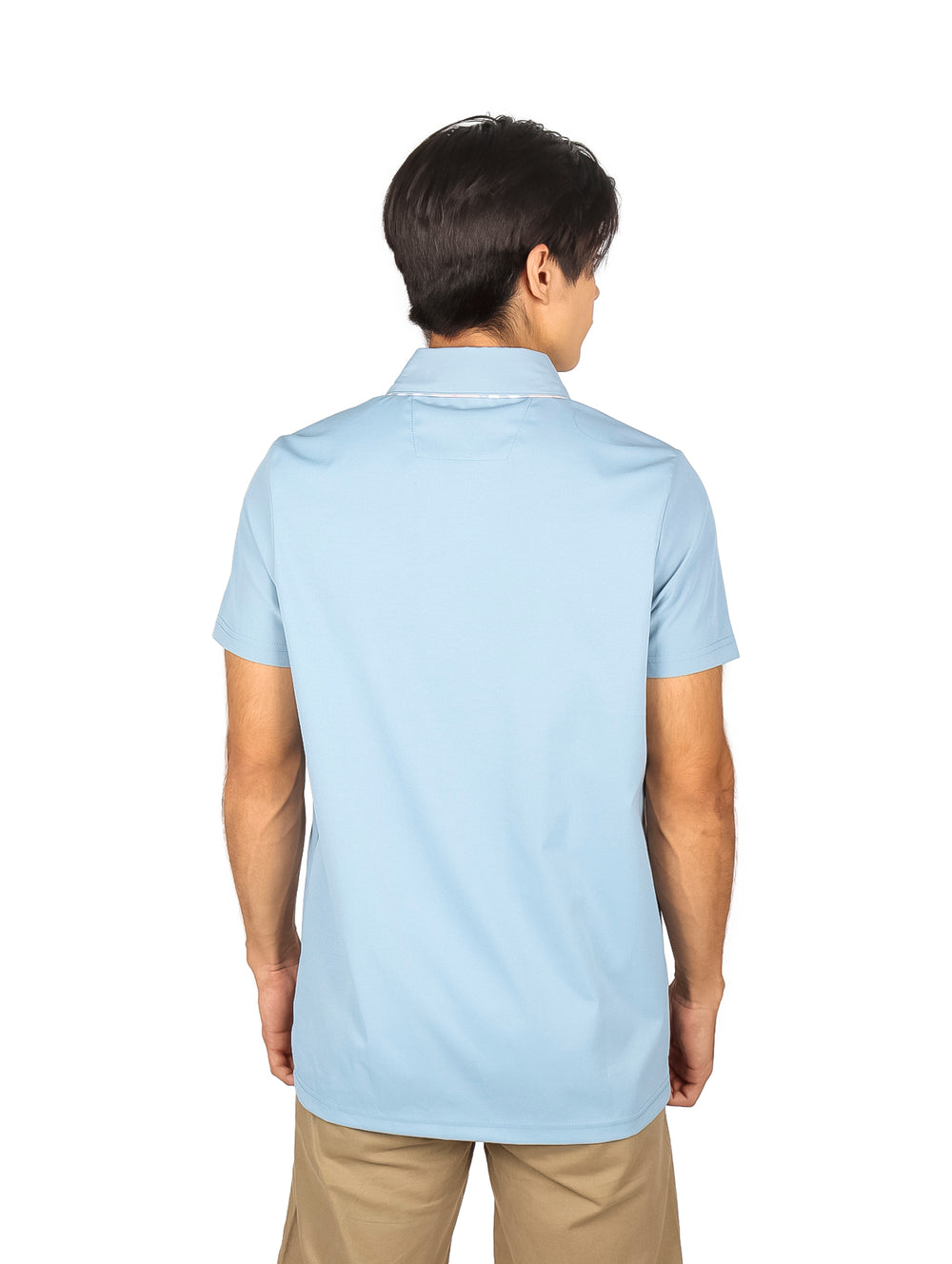 Hombre vistiendo una playera polo de color azul cielo con un pequeño parche marrón en el pecho.