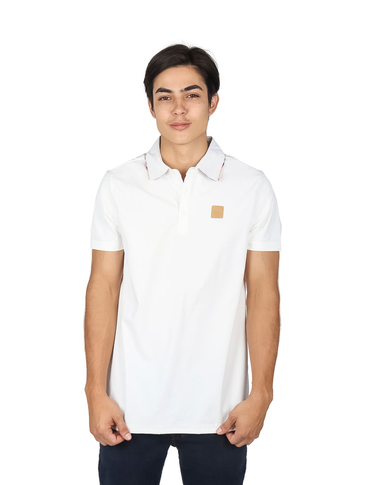 Hombre vistiendo una playera polo blanca de manga corta con un pequeño detalle beige en el pecho.