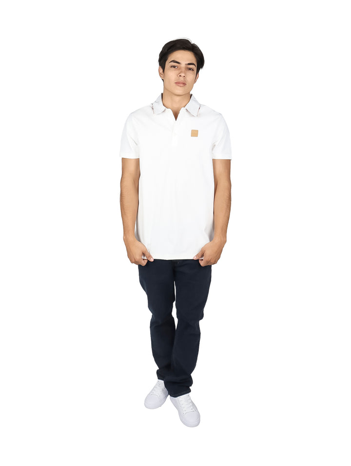 Hombre vistiendo una playera polo blanca de manga corta con un pequeño detalle beige en el pecho.