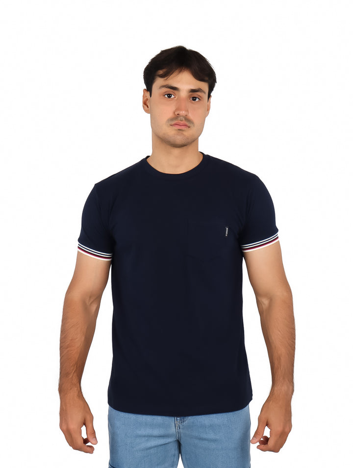 Hombre vistiendo playera azul marino de manga corta con detalles de rayas blancas y rojas en los bordes de las mangas.