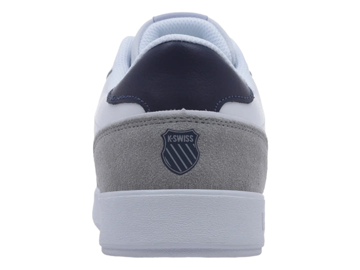 Tenis K-Swiss blancos con detalles en gris y azul marino, diseño casual deportivo.
