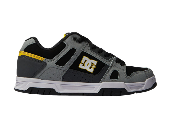 Tenis DC Shoes color gris y negro con detalles amarillos y suela blanca.