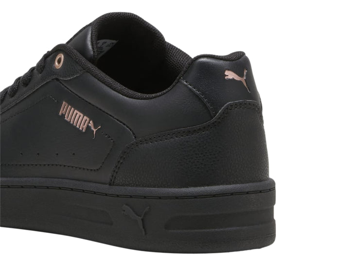 Tenis PUMA color negro con ojales en oro rosa y suela plana, estilo casual.