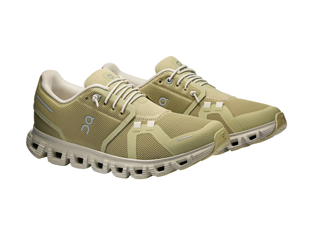 Tenis deportivos On Cloud color verde oliva con suela blanca y detalles en azul claro.