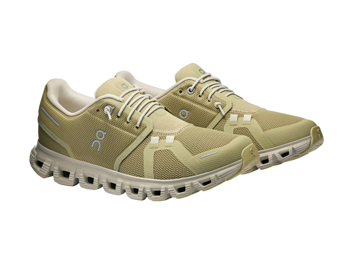 Tenis deportivos On Cloud color verde oliva con suela blanca y detalles en azul claro.