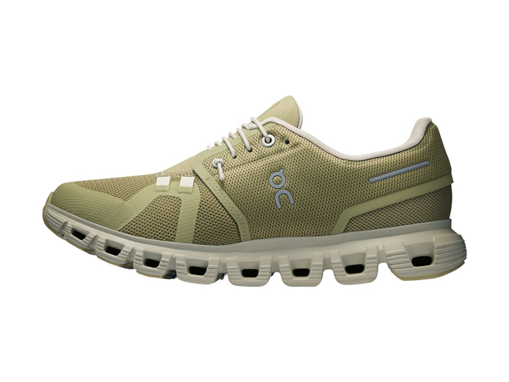 Tenis deportivos On Cloud color verde oliva con suela blanca y detalles en azul claro.