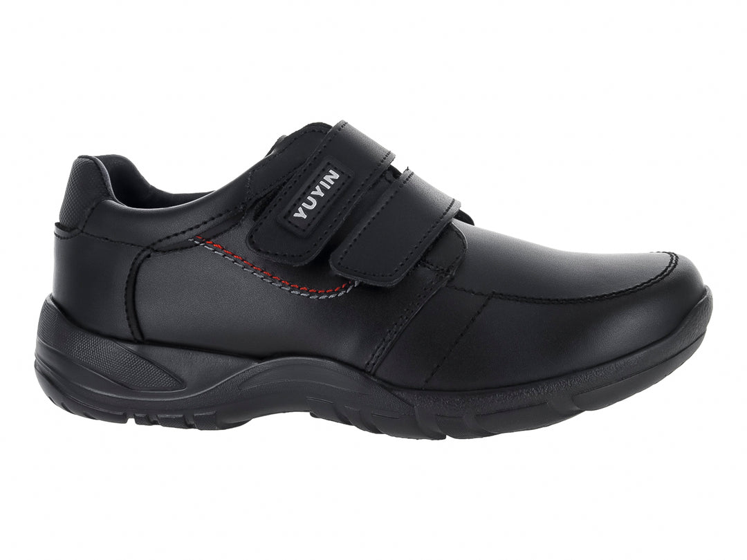 Zapato negro para niño con cierre de velcro y detalle de costura roja lateral.