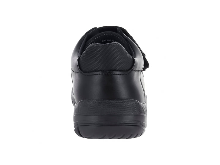 Zapato negro para niño con cierre de velcro y detalle de costura roja lateral.