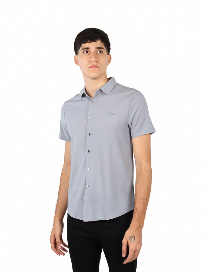 Hombre vistiendo una camisa de manga corta color gris con cuello y botones frontales.