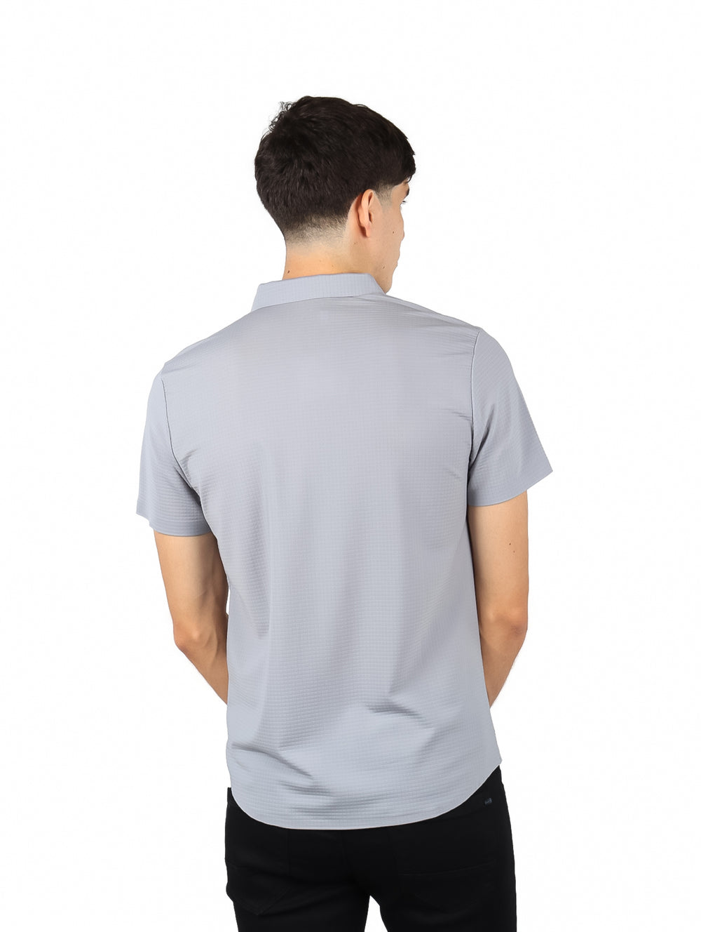 Hombre vistiendo una camisa de manga corta color gris con cuello y botones frontales.